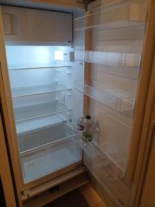 an empty refrigerator with its door open with a bottle in it at très bel appartement 2 pièces in Brétigny-sur-Orge