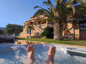 a persons feet in a swimming pool with a palm tree at La Maison Bleue in Toulon