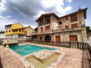 a house with a swimming pool in front of a building at Camino del Pinar in Quintanar de la Sierra