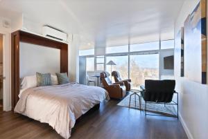 Un dormitorio con una cama y sillas y una gran ventana. en Iconic Modern Stay w Free Parking, en Spokane