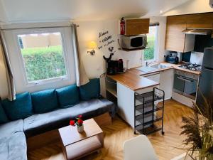 a small living room with a couch and a kitchen at LA PALMYRE LES MATHES Mobil home 3ch TOUT CONFORT 128 Camping 4 étoiles LES CHARMETTES in Les Mathes