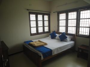 a bedroom with a bed with blue pillows and windows at Sanvika Hotels & Service Apartments in Coimbatore