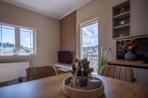 a dining room with a table with chairs and windows at Mamfredas Suites in Kypseli