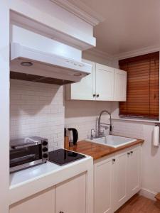 a white kitchen with a sink and a microwave at The Plateau Chateau in Queens +11 photos