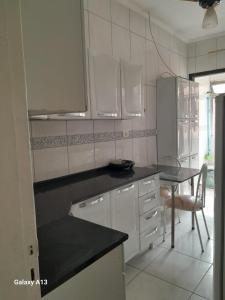 大普拉亚Lindo apartamento Vila Mirim的厨房里有白色的橱柜和一张桌子