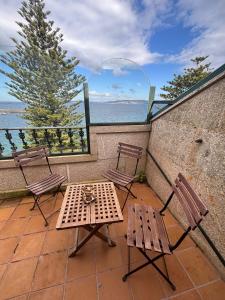 a table and chairs on a balcony with a view of the ocean at Duplex Bueu Vistas con terraza in Bueu