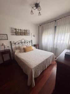 a bedroom with a bed with a white comforter at Duplex Bueu Vistas con terraza in Bueu