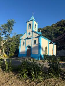 a blue and white church with a clock tower at Chalé da Luz - visconde de Mauá in Resende