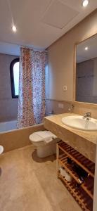 łazienka z umywalką, toaletą i lustrem w obiekcie Apartamento de tres dormitorios muy espacioso con jardines y piscinas w mieście Estepona
