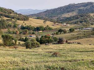 a view of a field of grass with mountains in the background at Sítio no interior de SP para curtir a Natureza in Águas da Prata