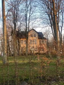a large house in the middle of a field with trees at Pałac Poraj in Wicko