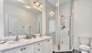 a white bathroom with two sinks and a shower at XTO Hotel in Markham