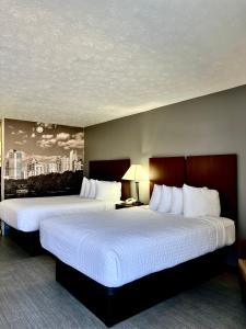two beds in a hotel room with a view of a city at Clarion Pointe Morrow - Atlanta South in Morrow
