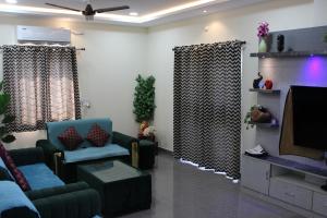 a living room with couches and a flat screen tv at Willow the Villa in Hyderabad