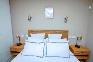 a bedroom with a bed with white sheets and pillows at The Bush Cottage at Mokolodi Gaborone in Gaborone