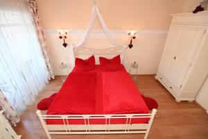 a bedroom with a red bed with red pillows at Appartement Romantik in Warnemünde