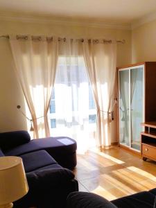 a living room with a couch and a large window at Welkome Inn Estádio T2 in Portimão