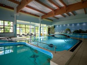 a large indoor swimming pool with blue water at Apartament POD SŁOŃCEM BAŁTYKU w Perle Mórz-Ustronie Morskie Sianożęty in Sianozety