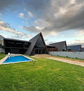 a house with a swimming pool in front of a building at Qafqaz Wood Chalet in Gabala