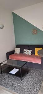 eine Couch mit Kissen und einem Tisch in einem Zimmer in der Unterkunft Appart'Jardin in Saint-Pierre-des-Corps