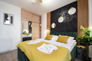 a bedroom with a yellow bed with towels on it at Apartament POD SŁOŃCEM BAŁTYKU w Perle Mórz-Ustronie Morskie Sianożęty in Sianozety +14 photos