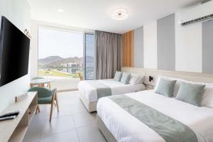 a hotel room with two beds and a television at Porto Horizonte Apartamentos in Santa Marta