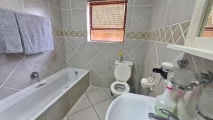 a bathroom with a tub and a toilet and a sink at Sunset Walk Self Catering Guest House in Jeffreys Bay +12 photos