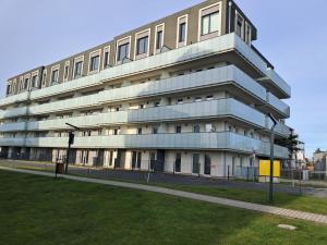 a tall apartment building with a lawn in front of it at Apartament POD SŁOŃCEM BAŁTYKU w Perle Mórz-Ustronie Morskie Sianożęty in Sianozety