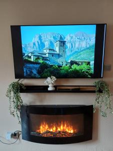 a flat screen tv above a fireplace with a castle at Apartamento con vistas al Parque Nacional de Ordesa y Monteperdido in Torla