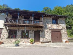 a stone building with a balcony and two doors at The living mountain - SAJA - CASONA RURAL in Saja