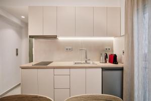 a kitchen with white cabinets and a sink at La Stella Apartment Thisio in Athens