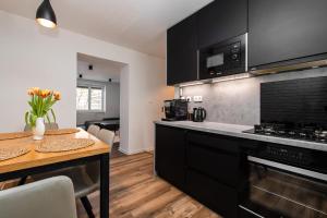 una cucina con armadi neri e tavolo in legno di Útulný a štýlový apartmán v centre mesta a Prešov