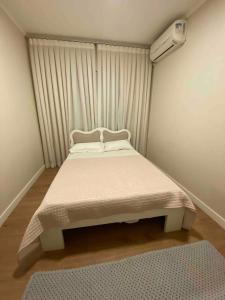 a bedroom with a white bed with a window at Apartamento familiar próximo à Universidade in Tubarão +18 photos