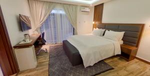 een hotelkamer met een bed, een bureau en een raam bij Centurion Aparthotel in Abuja
