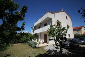 a white house with a car parked in front of it at Dolce Mare Apartmani in Pakoštane