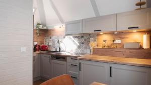 a kitchen with white cabinets and a wooden counter top at Haus 99, Dorf 3 mit Sauna & Whirlpool in Kirchheim