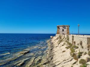 an old building on the edge of a cliff next to the ocean at Vida Rooms in Trapani