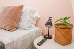a lamp on a table next to a couch with a plant at Apê de 3 quartos com ar-condicionado e Berço in Cuiabá