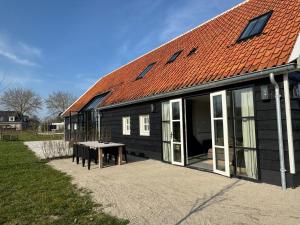 ドンブルグにあるVrijvakantiehuis Brouwerijweg 45aの赤い屋根とテーブルのある黒い建物