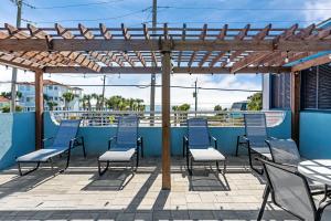 a patio with blue chairs and a wooden pergola at Beachside Inn in Destin