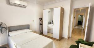 a white bedroom with a bed and a mirror at Madinaty apartment 2 شقة فندقية مفروشة سوبر لوكس في مدينتي in Madinaty +28 photos
