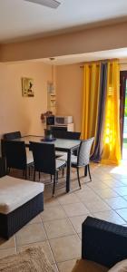 a dining room with a table and chairs and yellow curtains at Vue mer et montagne in Vieux-Habitants