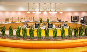 a restaurant lobby with a counter with plants at Buena Vista Suites Orlando in Orlando