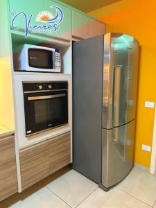eine Küche mit einem Kühlschrank aus Edelstahl und einer Mikrowelle in der Unterkunft Apart Hotel As Vieiras in Tamandaré + 29 Fotos