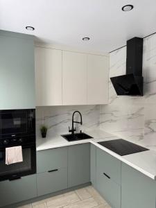 a white kitchen with a sink and a microwave at Торайгырова 89 in Pavlodar