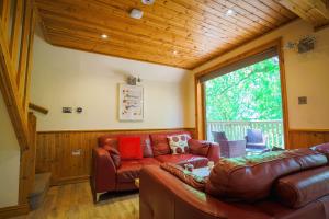 a living room with a couch and a large window at Fern Gully Lodge with Hot Tub - Spa Resort - Devon in Chudleigh