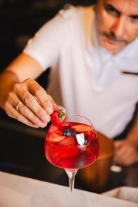 a woman placing a strawberry in a red drink at Crowne Plaza Madrid - Centre Retiro by IHG in Madrid