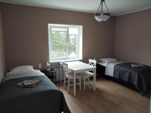 a bedroom with two beds and a table and a window at Apartment by the bar in Imatra