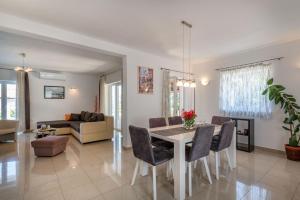 Un comedor y una sala de estar con mesa y sillas. en Villa Sandra, a beautiful villa with sea view and a pool, en Drenje