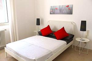 a white bed with red pillows in a bedroom at La Villa in Salve